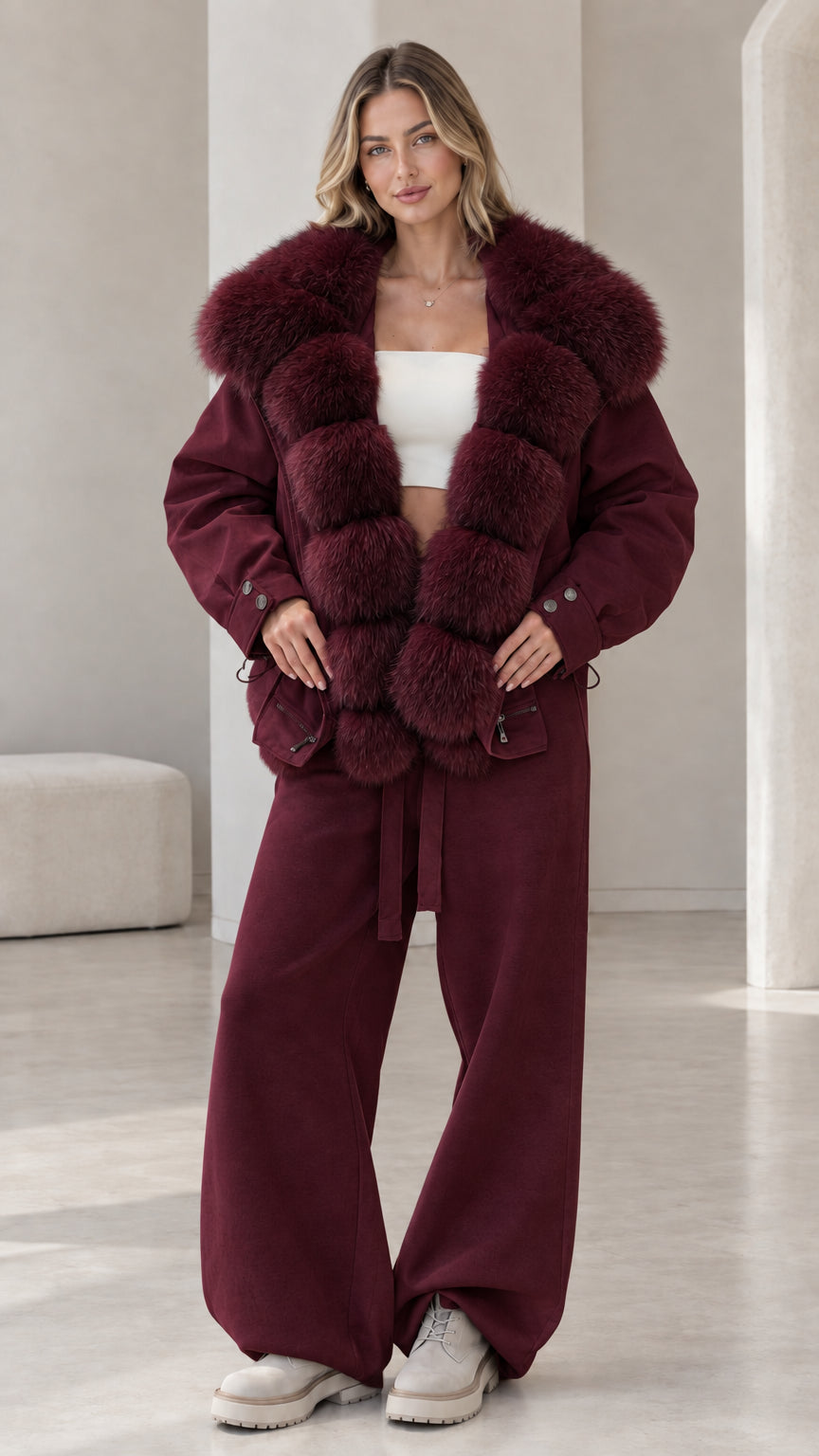 Model wearing deep burgundy jacket and pants set with matching wine plush collar