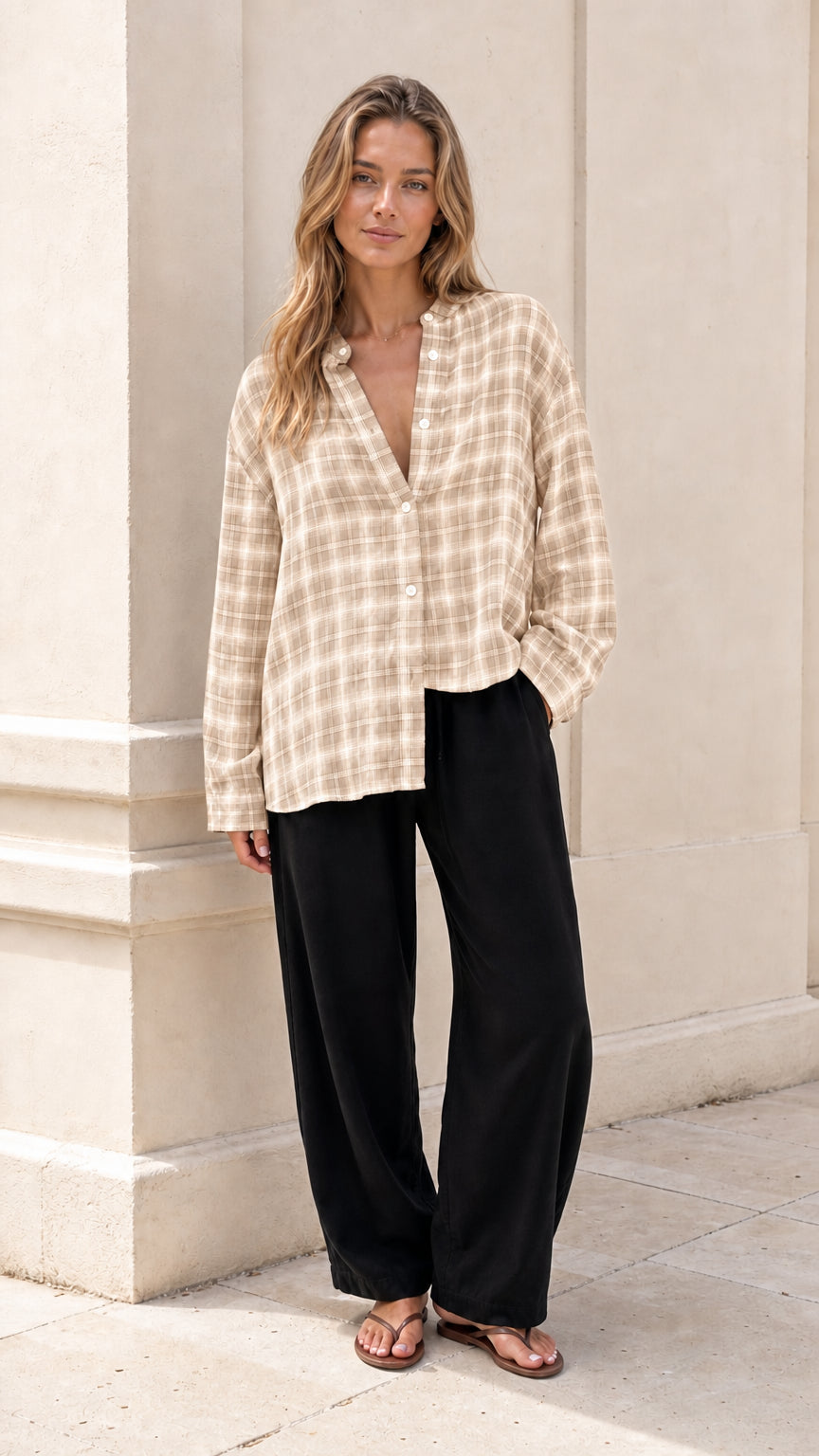 Model wearing beige plaid button-down blouse with black trousers