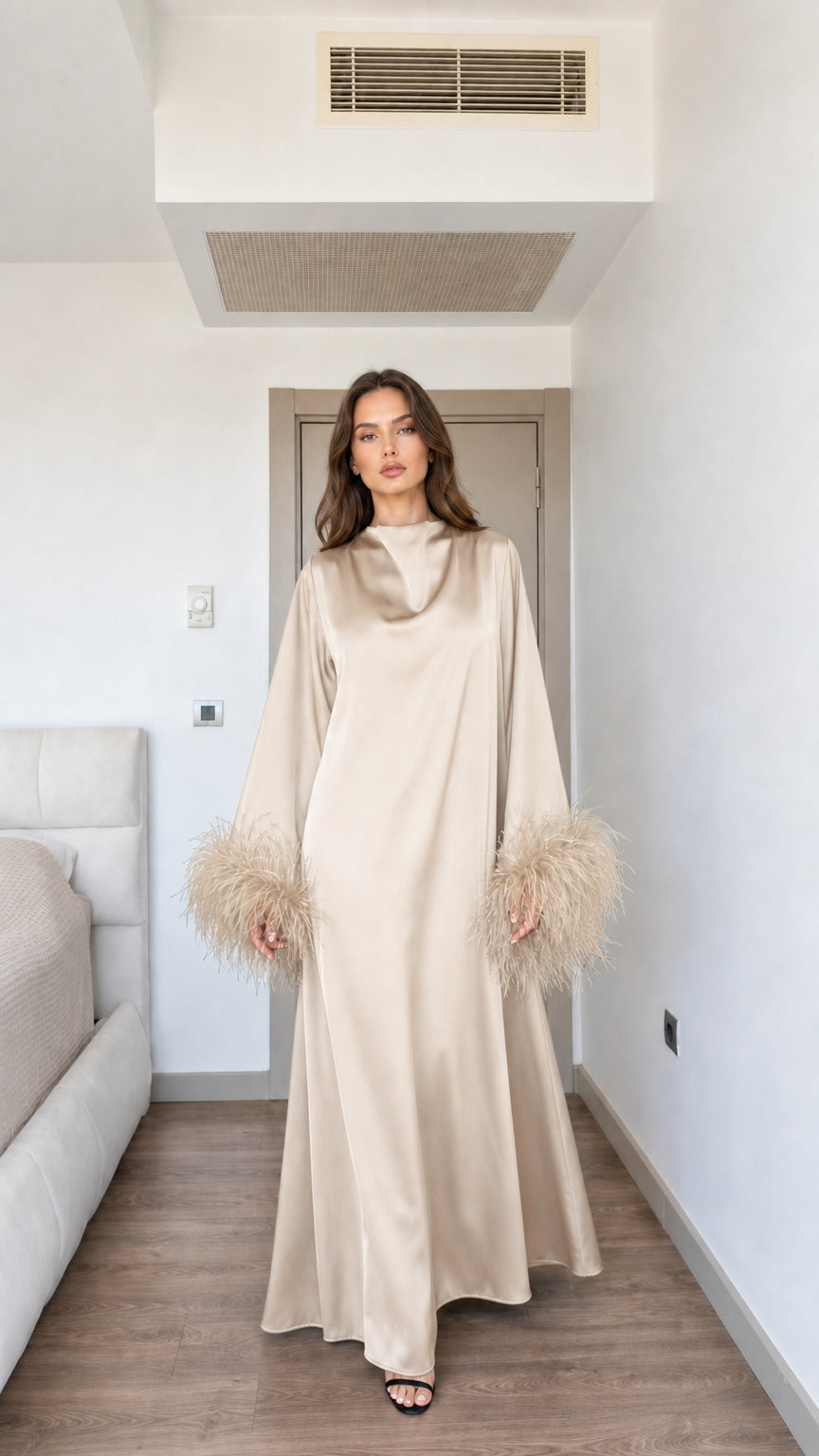 Model wearing elegant champagne beige satin maxi dress with feather cuffs