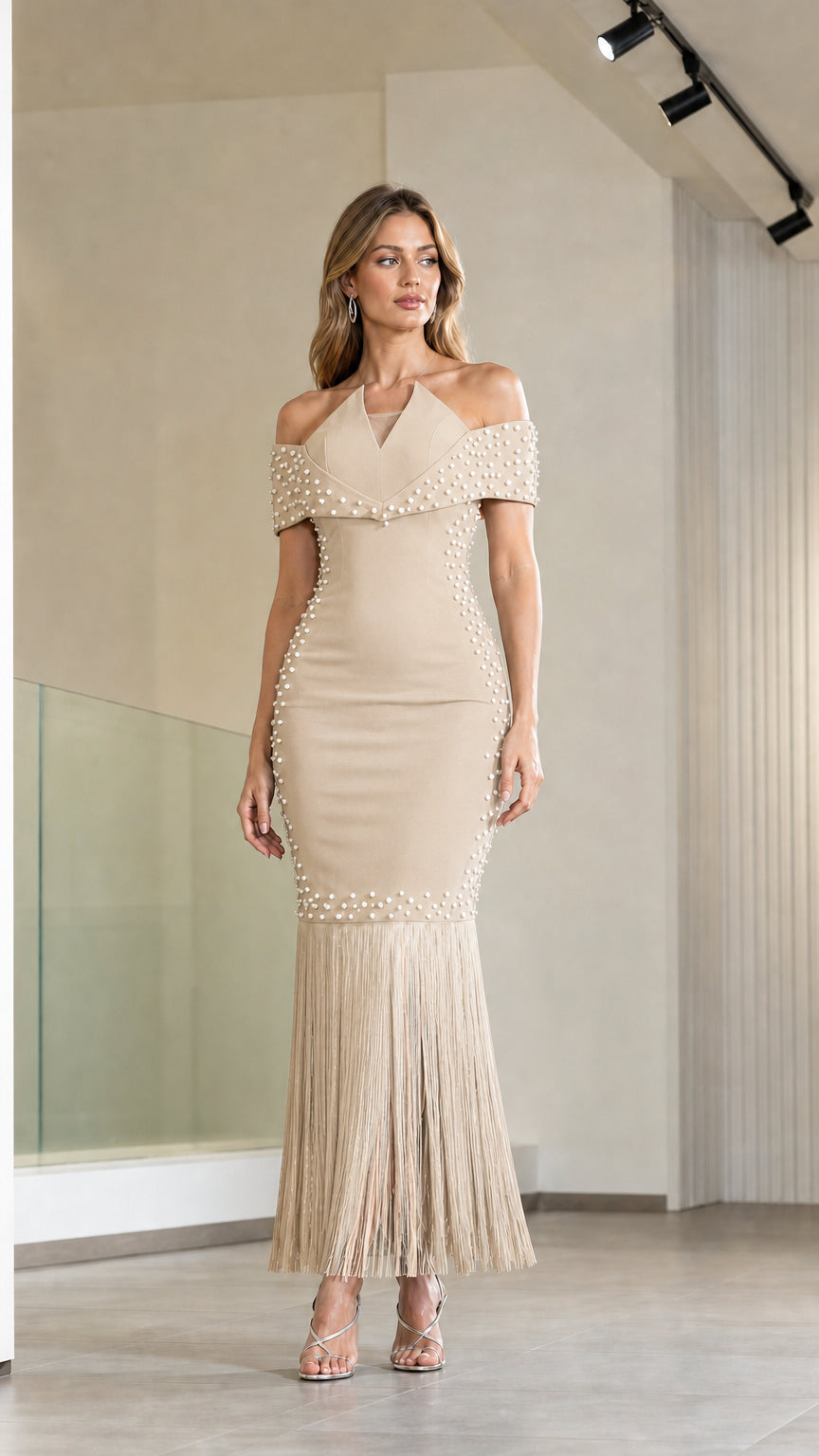 Model wearing champagne beige off-the-shoulder pearl embellished fringe evening dress