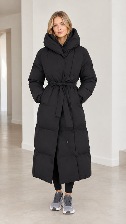 Front view of model wearing full-length black belted maxi puffer coat with hood