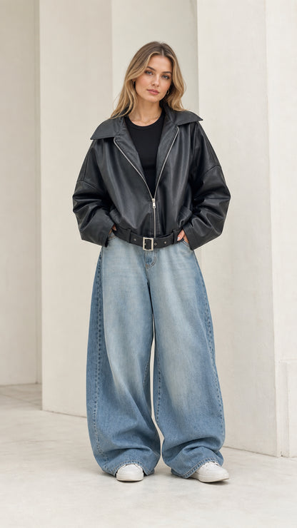 Full front view of model wearing black oversized faux leather jacket with wide-leg jeans