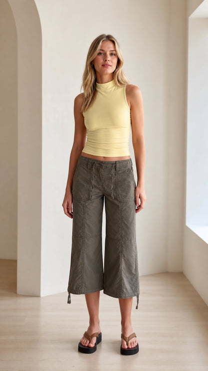 Full front view of model wearing light yellow mock neck sleeveless tank top with olive cargo pants