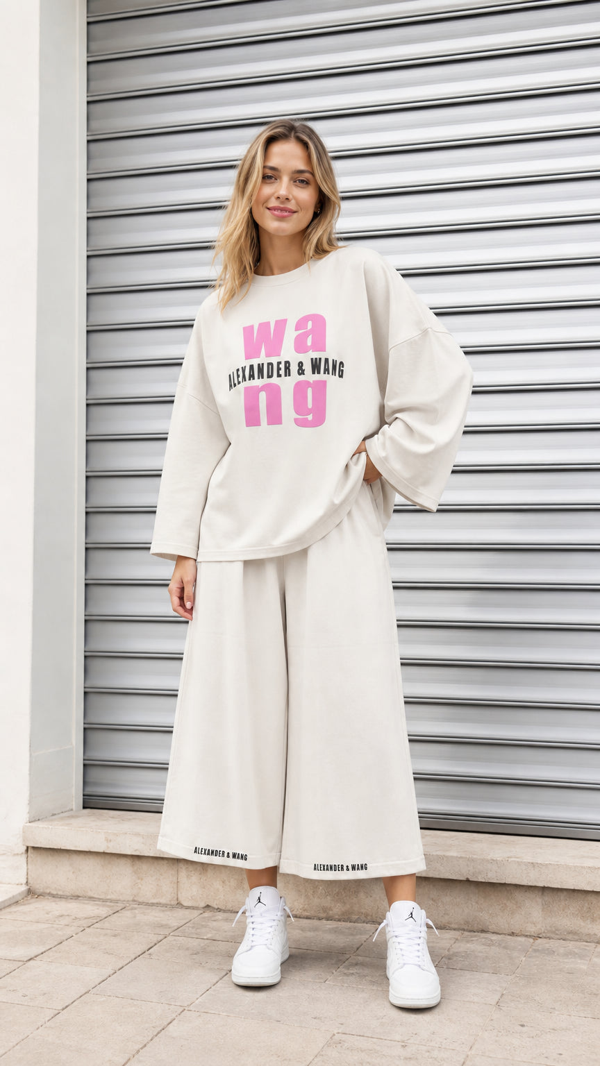 Front view of model wearing cream oversized graphic sweatshirt and wide leg cropped lounge pants set