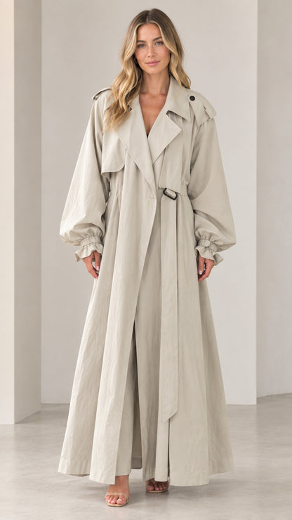Full-length front view of woman wearing beige maxi trench coat with lantern sleeves and belt