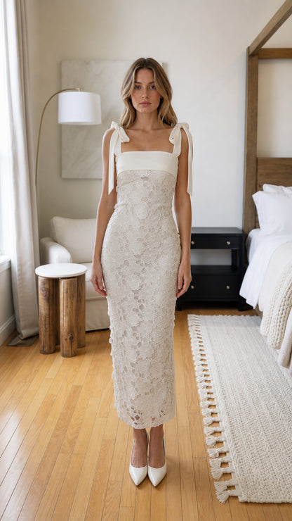 Front view of woman wearing white lace midi dress with bow straps