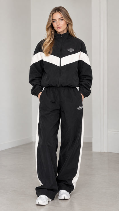 Front view of woman wearing black and white chevron colorblock tracksuit set with wide leg pants
