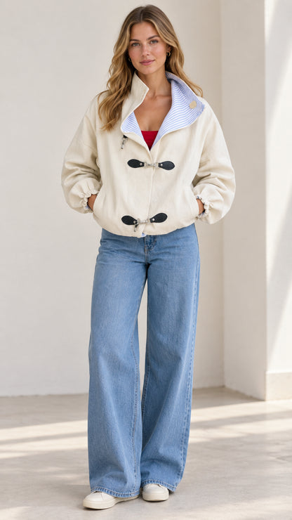 Front full-length view of a woman wearing the beige clasp buckle bomber jacket with wide-leg jeans