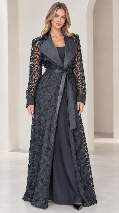 Front view of model wearing black floral lace maxi trench coat with satin lapels