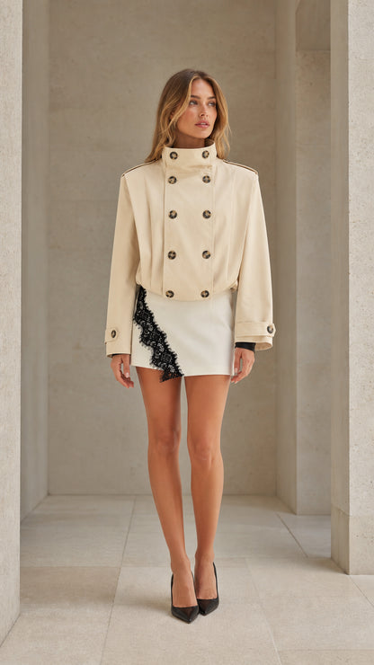 Front full view of woman wearing cream cropped double-breasted trench jacket with stand collar