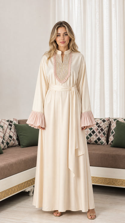 Front full-length view of woman wearing cream embroidered modest maxi abaya dress with pleated cuffs