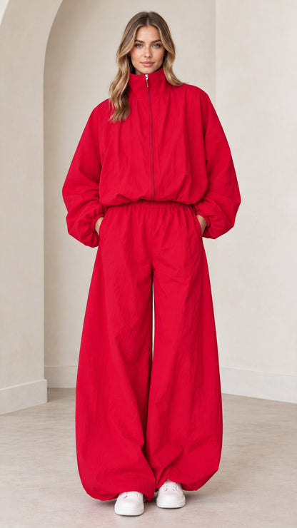 Front full view of woman wearing bright red zip-up parachute jumpsuit with wide legs