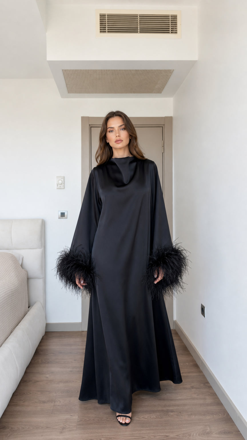 Front full view of model wearing black satin long sleeve maxi dress with feather cuff details