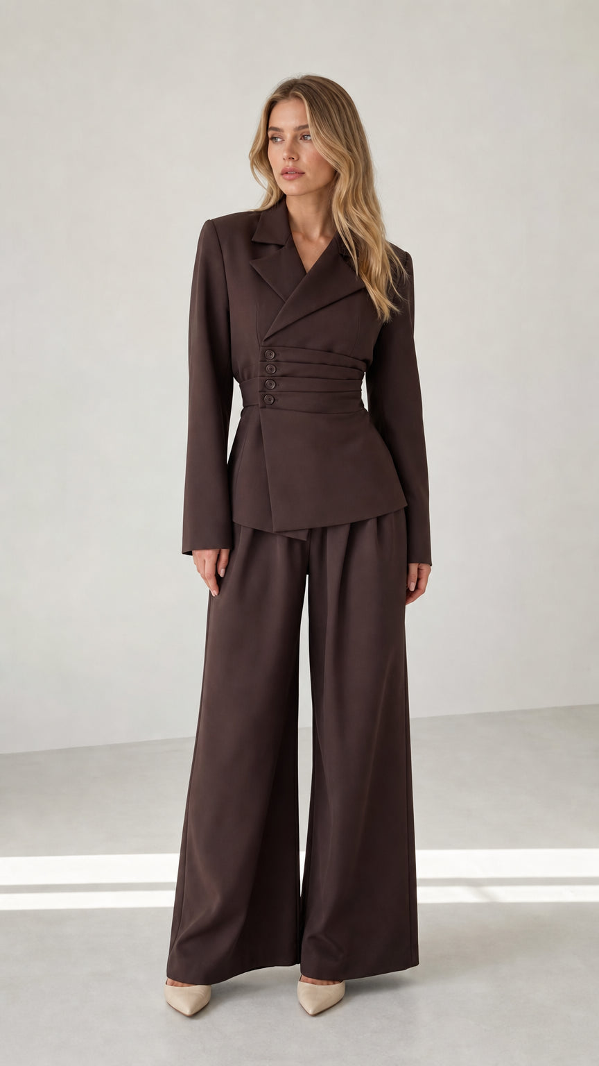 Front view of woman wearing chocolate brown cinched waist blazer and wide leg trousers set
