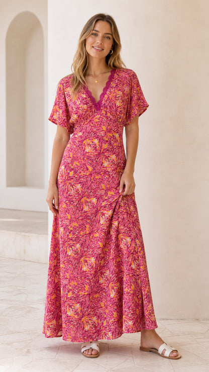 Front full-length view of model wearing fuchsia pink floral V-neck maxi dress with lace trim