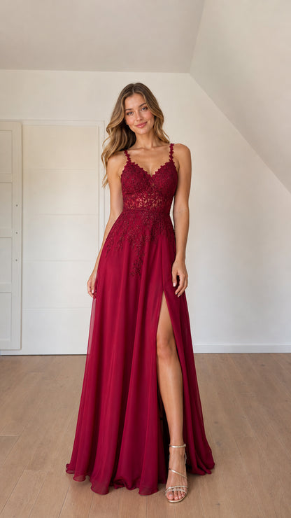 Front view of woman wearing burgundy lace applique A-line chiffon formal gown with leg slit