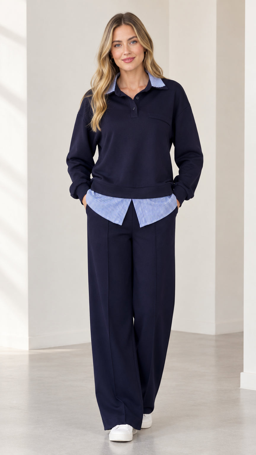 Front view of woman wearing navy blue 2-piece faux layered collared sweatshirt and wide leg pants set