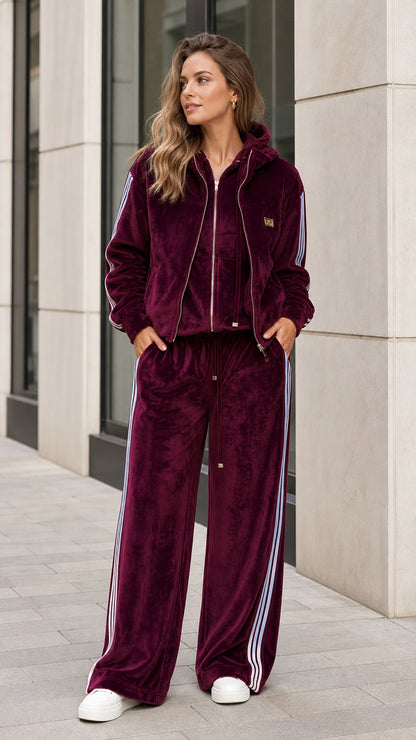 Front view of woman wearing burgundy velour zip-up hoodie and wide-leg tracksuit set with side stripes