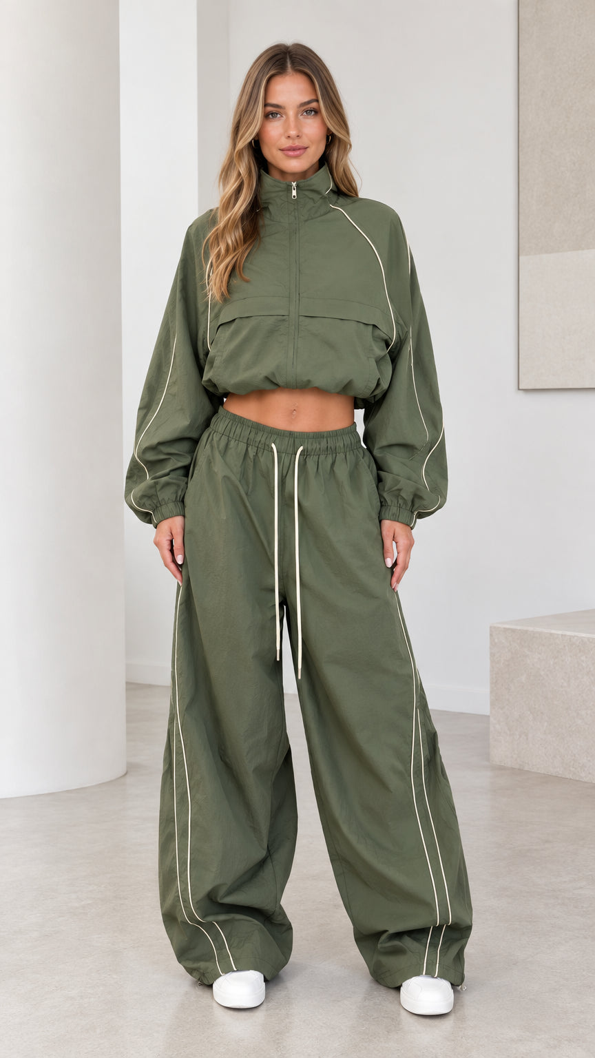 Front view of model wearing olive green cropped windbreaker jacket and wide leg parachute pants set