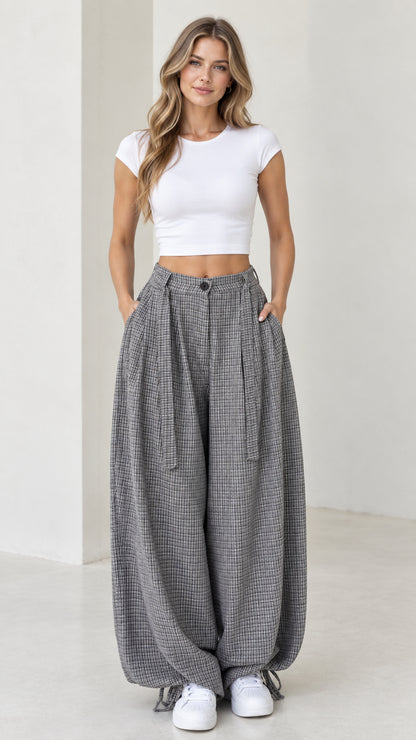 Front view of woman wearing grey micro-plaid pleated balloon pants with white crop top