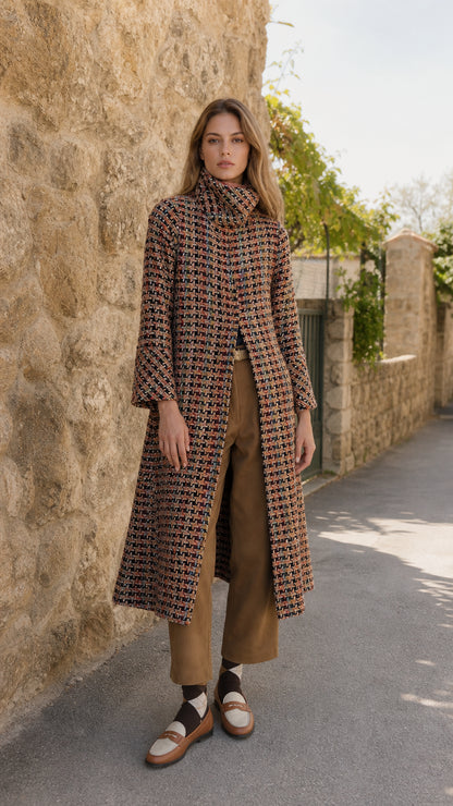 Full front view of model wearing rust multi high neck tweed long coat with brown trousers and loafers