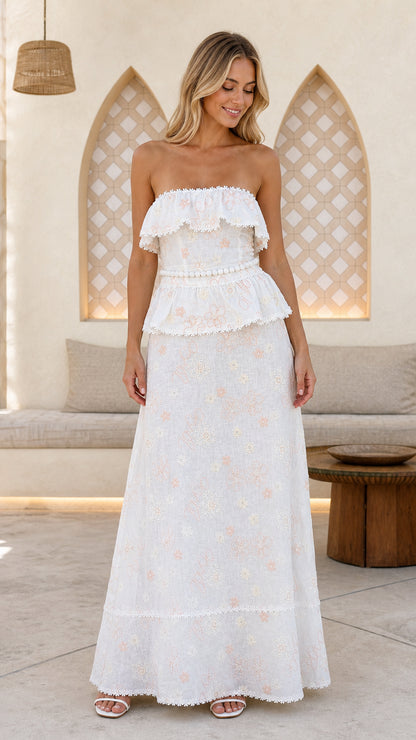 Front view of woman wearing white strapless floral embroidered ruffle maxi dress