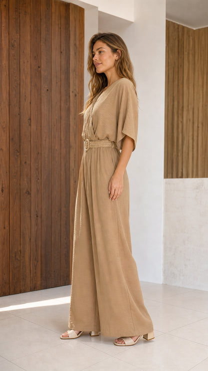 Side profile of woman in beige wide-leg jumpsuit with woven belt