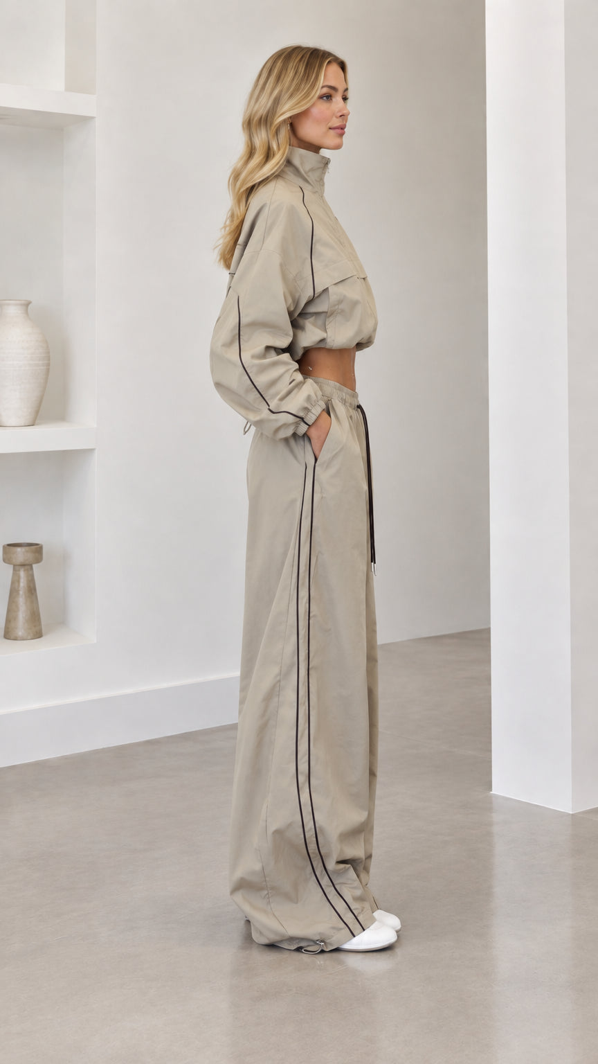 Side profile view of model wearing taupe two-piece windbreaker tracksuit set