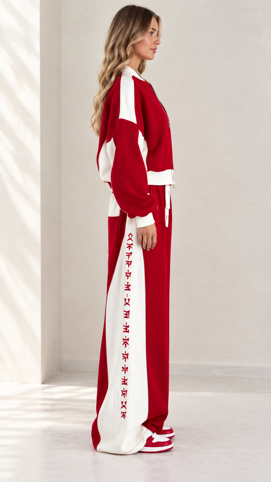 Side profile view of model wearing red and white contrast stripe tracksuit set