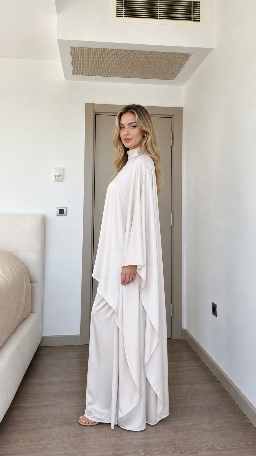 Side full view of woman wearing Cream satin cape tunic and wide-leg trousers