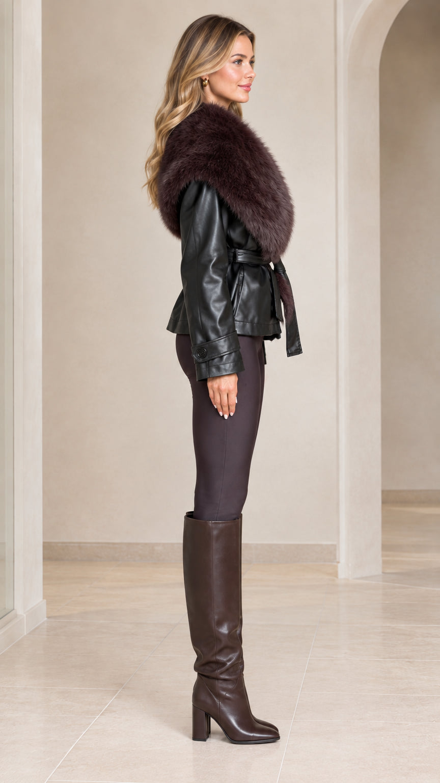 Side profile view of model wearing black belted faux leather jacket with plush collar