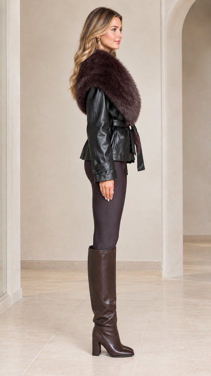 Side profile view of model wearing black belted faux leather jacket with plush collar