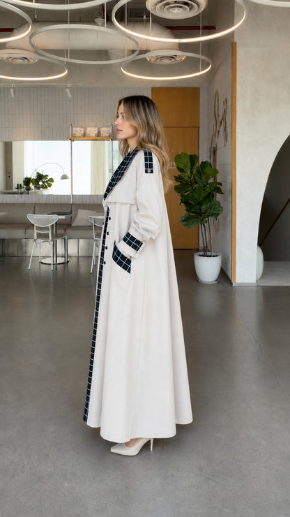 Side angle view of model wearing off white maxi longline duster coat with grid plaid trim