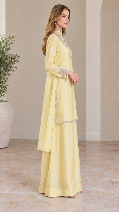 Side profile of model wearing pale yellow embellished satin tunic and trousers set