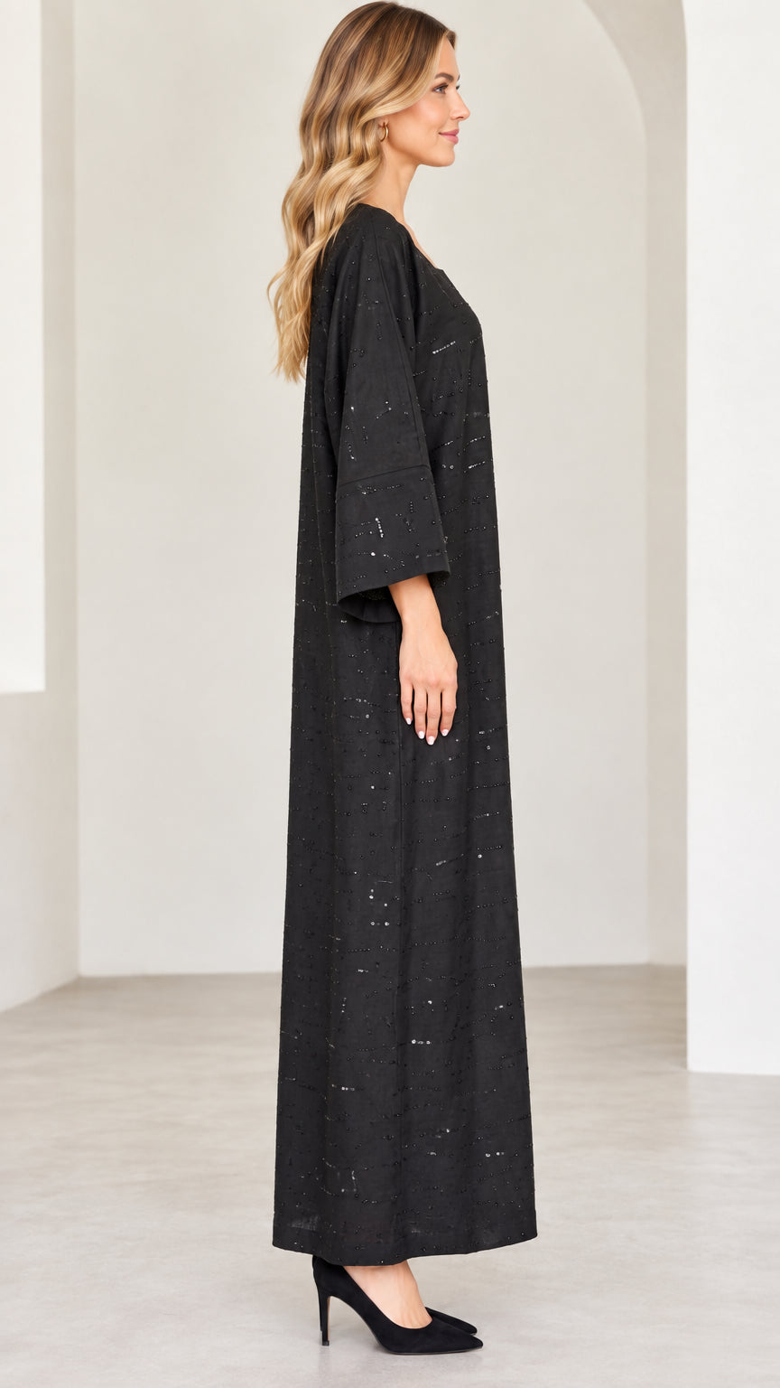 Side profile view of model wearing black loose fit sequin kaftan dress