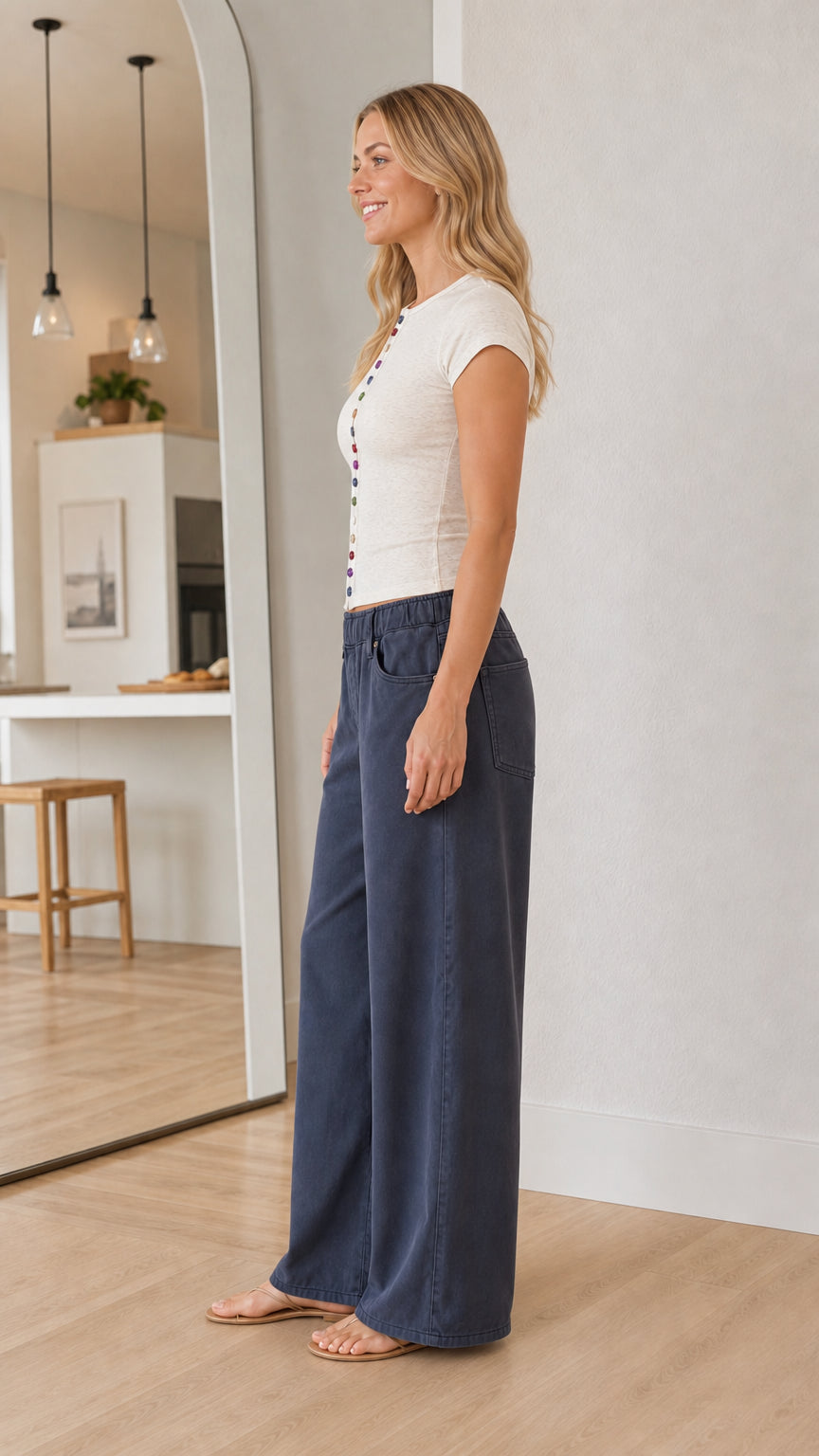 Side profile view of a model wearing an off-white fitted short sleeve tee and blue trousers