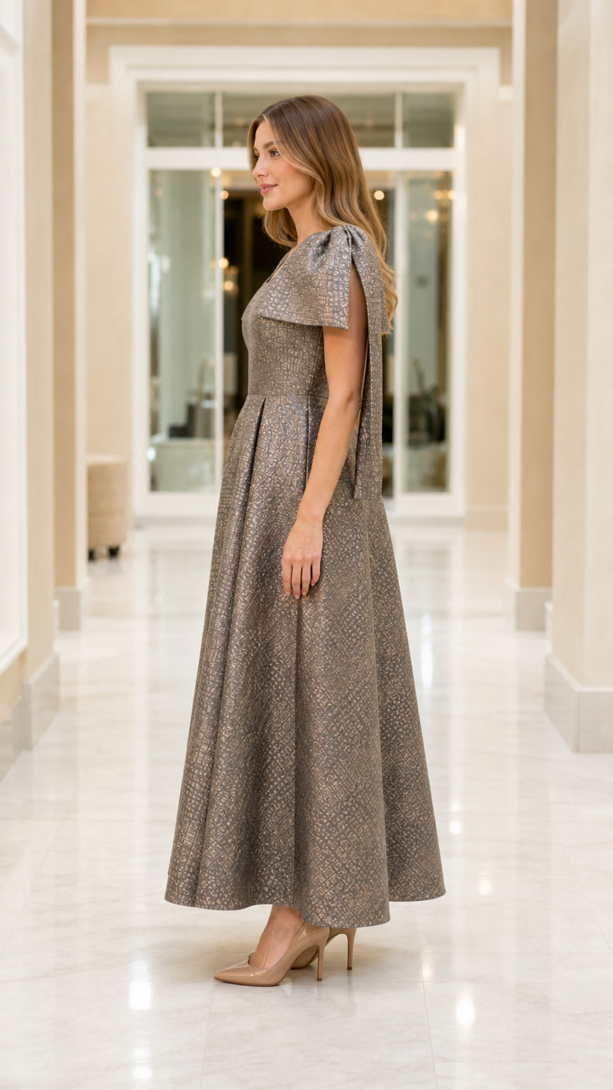 Side view of model in metallic jacquard maxi gown with structured cape sleeves