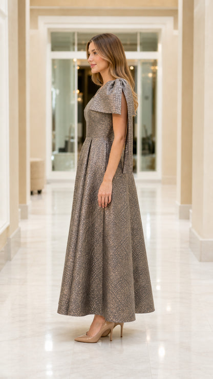 Side view of model in metallic jacquard maxi gown with structured cape sleeves