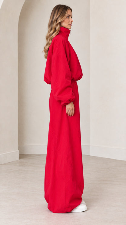 Side profile view of red long-sleeve parachute jumpsuit with elastic waist
