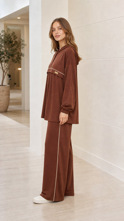 Side profile of woman wearing brown 2-piece hooded lounge set with side piping