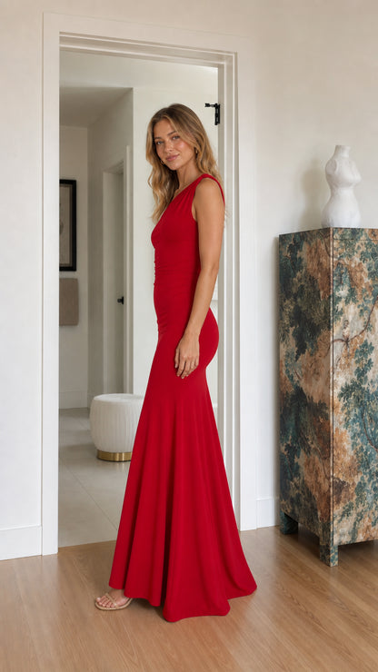 Side profile of model in a fitted red one-shoulder floor-length gown