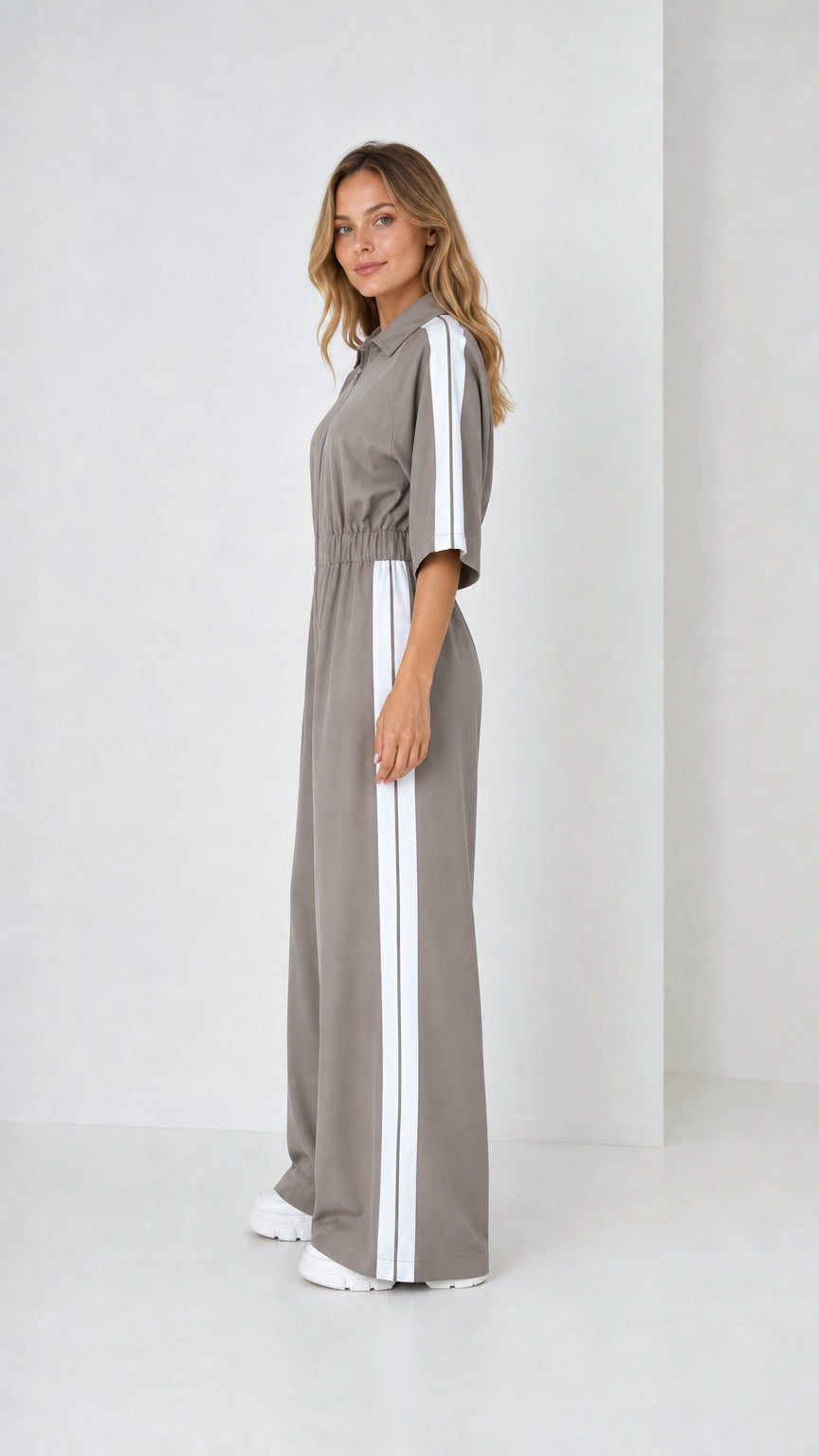 Side view of woman wearing taupe grey zip front track jumpsuit