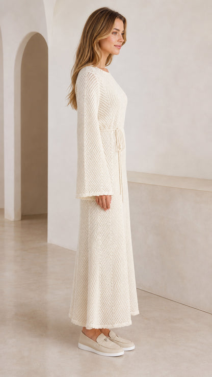 Side profile of model in cream long knit maxi dress with bell sleeves