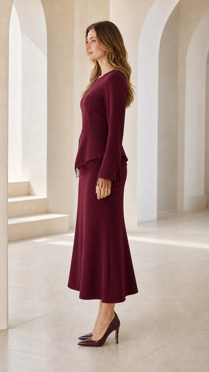Side view of model wearing burgundy long sleeve peplum midi dress