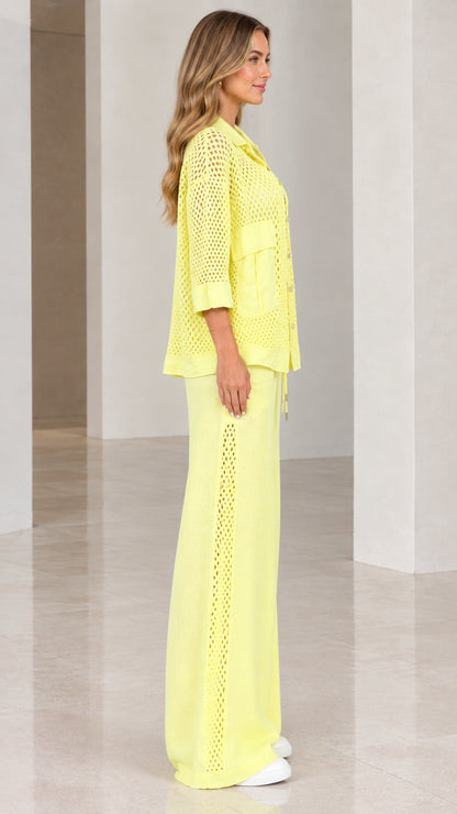 Side profile view of woman wearing light yellow open knit pants set