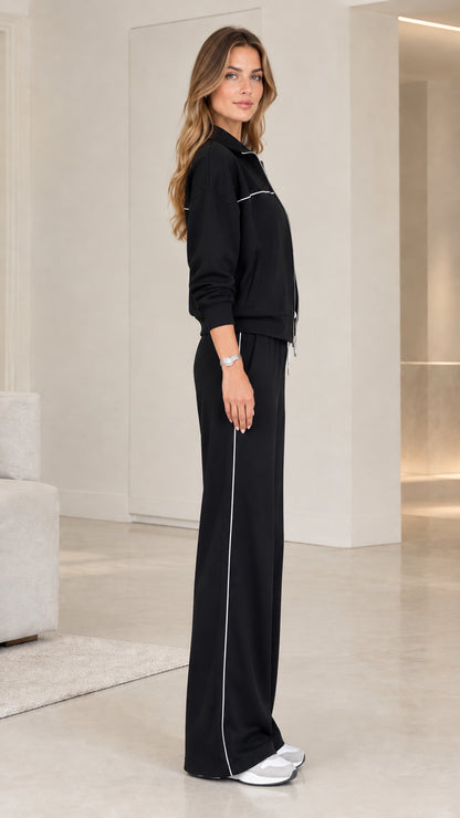 Side profile view of model wearing black two-piece wide-leg lounge track set