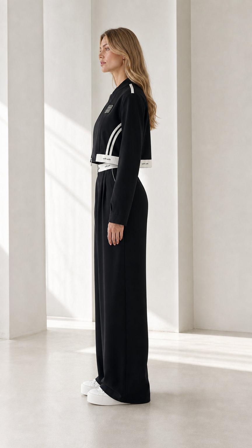 Side profile of model wearing black cropped jacket and wide-leg pants set