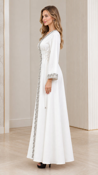 Side profile of woman wearing white embroidered full-length kaftan gown