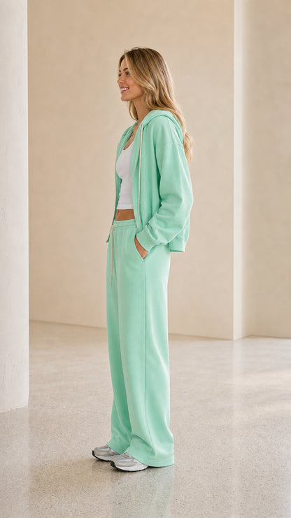 Model wearing mint green tracksuit side view