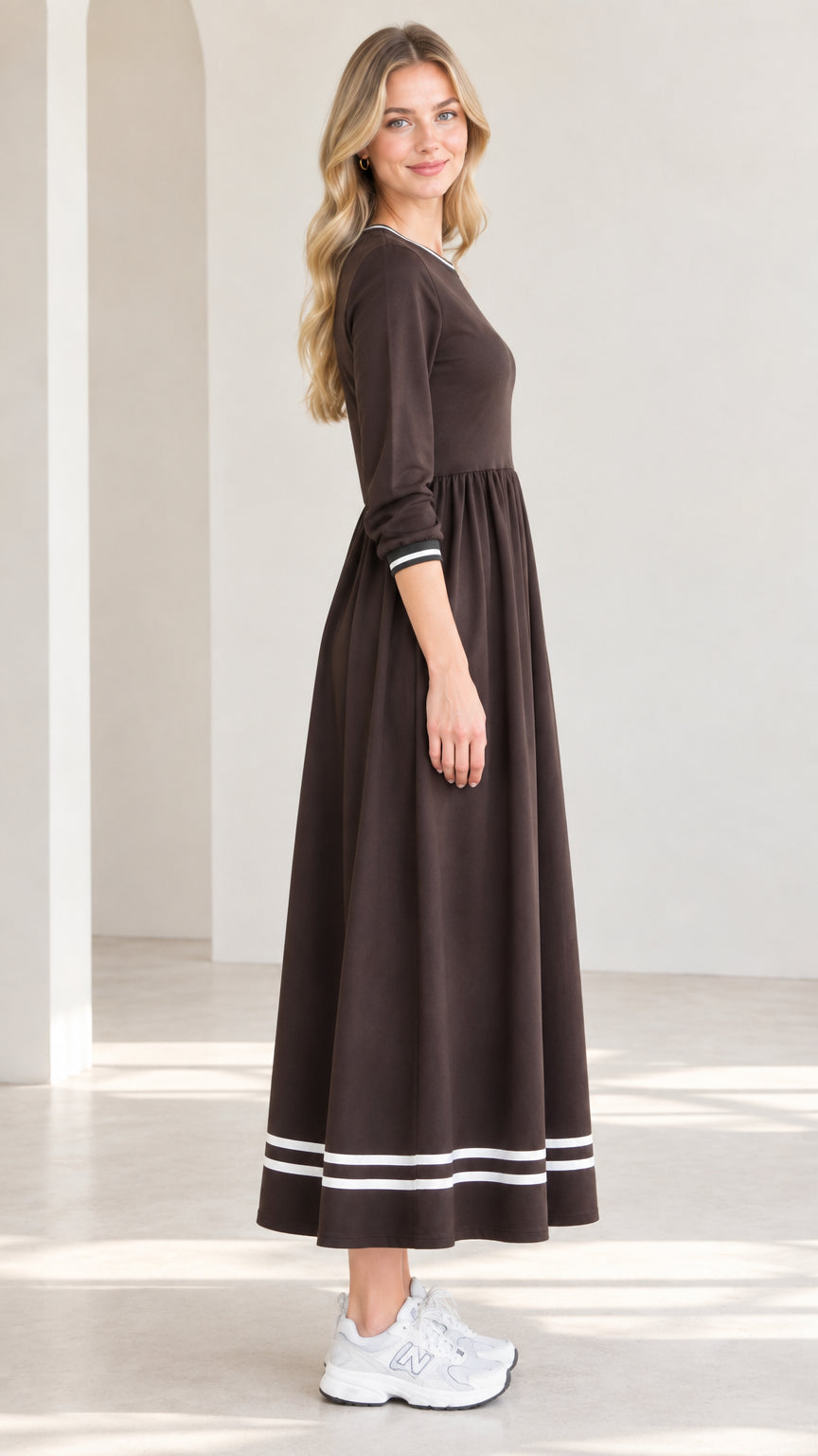 Side profile view of woman modeling brown contrast stripe trim maxi dress